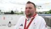 Rob Davies, smiling, in a Paralympics GB tracksuit with a red lanyard and medal, being interviewed outdoors in Paris