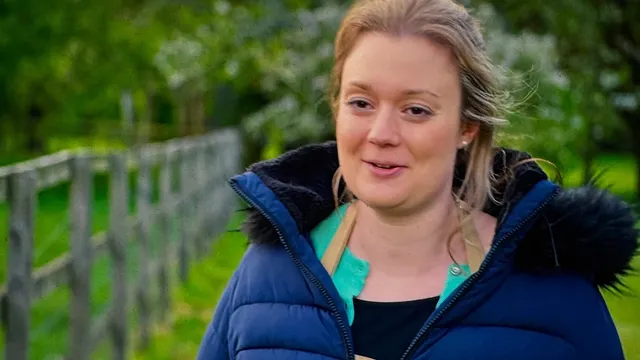 Rosie Brandreth-Poynter by a wooden fence outside the tent, in a blue padded coat, mid-sentence