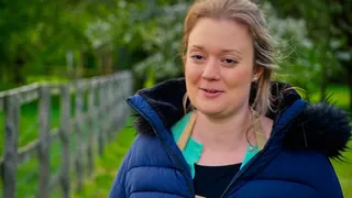 Rosie Brandreth-Poynter by a wooden fence outside the tent, in a blue padded coat, mid-sentence