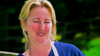 Stacey Hart outside the tent, eyes screwed shut, beaming, in a blue top and the show's apron