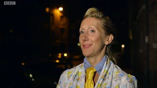 Tamara outside at night in a patterned jacket, blue collar and yellow tie, smiling