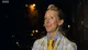 Tamara outside at night in a patterned jacket, blue collar and yellow tie, smiling