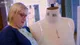 Tracey at her mannequin in glasses and a navy top over a bee-print shirt, looking down at the pale green lace bra she has made